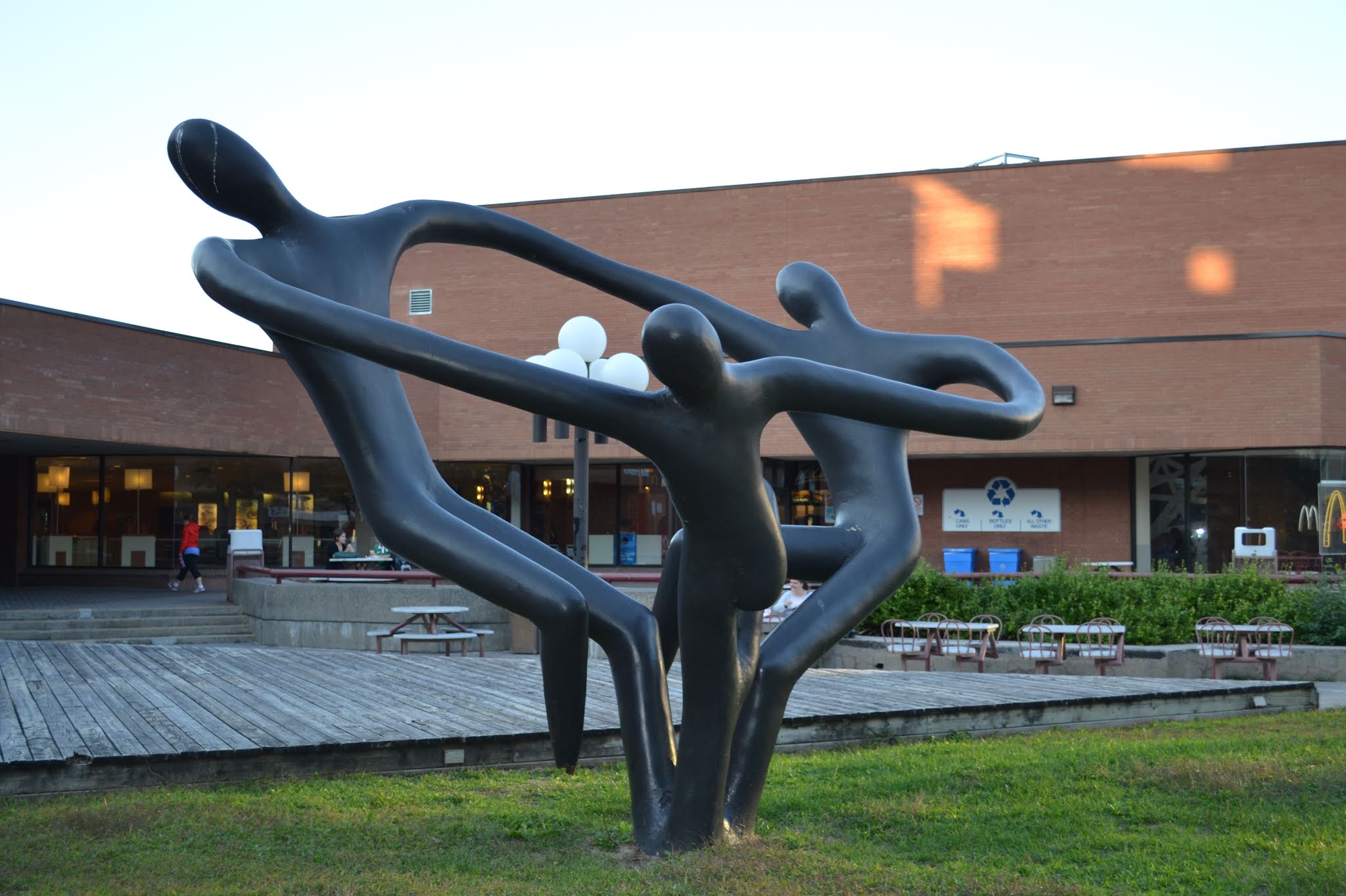 Large bronze figurative sculpture outside Peterborough Square at dusk