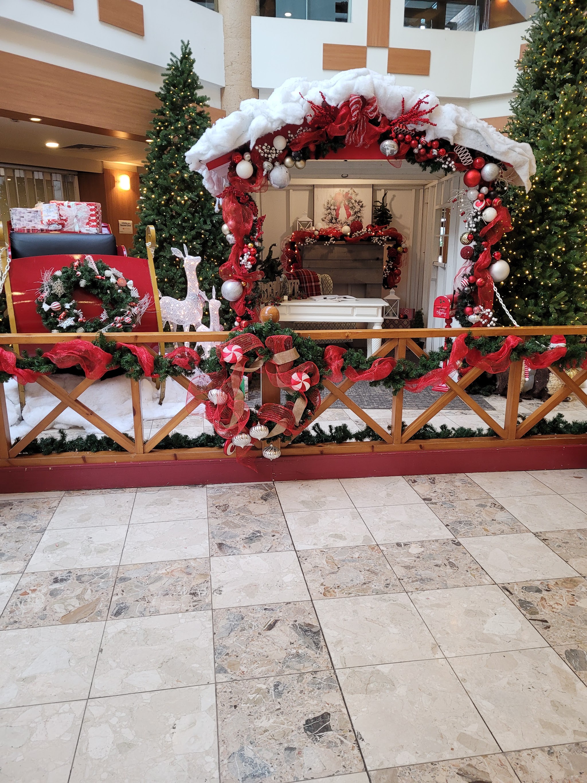 Christmas display in the Peterborough Square atrium with a red sleigh, decorated trees and a cozy fireplace scene